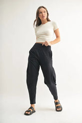 Woman modeling MONO B Flowbarrel High Waist Active Pants in black with a fitted top and sandals.